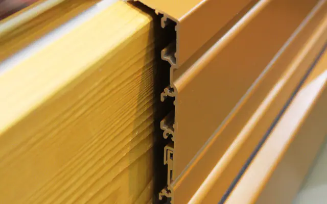 Coupe rapprochée d’un profil de fenêtre bois protégé par un capotage aluminium