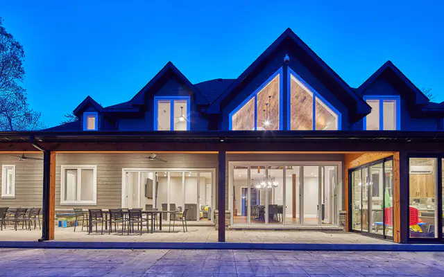 Maison contemporaine éclairée au crépuscule avec de larges baies vitrées