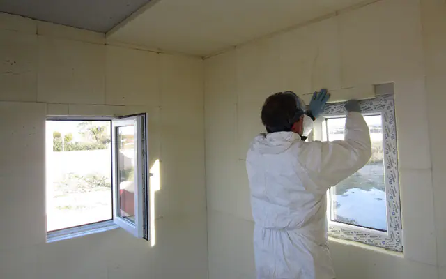 Poseur appliquant un panneau isolant autour d’une fenêtre neuve